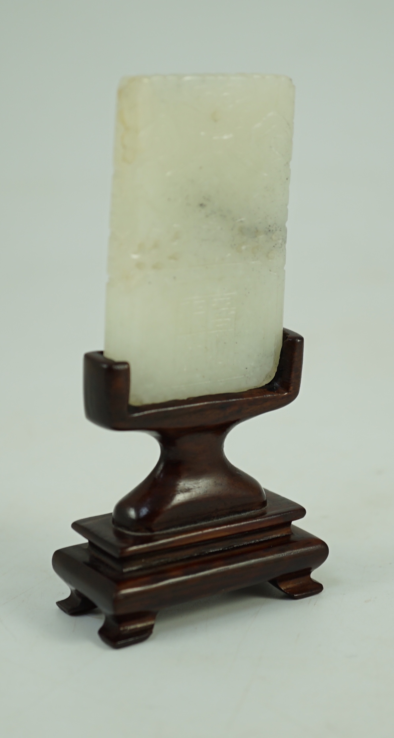A Chinese inscribed white jade plaque, 19th century, 6.3 cm high, excluding wood stand